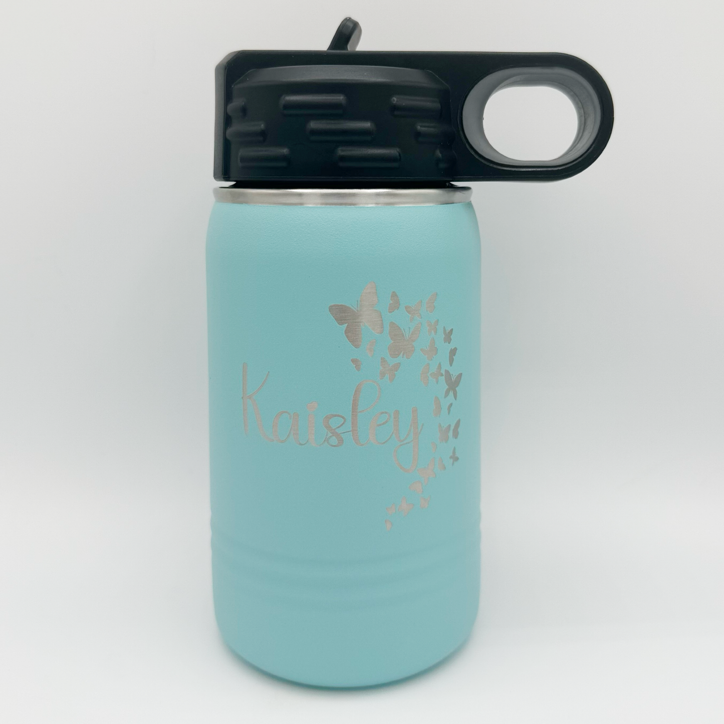 "Custom personalized light blue Polar Camel 12oz stainless steel kids' water bottle with a black flip-top lid and handle. The bottle features an elegant engraved design of fluttering butterflies along with the name 'Kaisley' in a graceful script font."