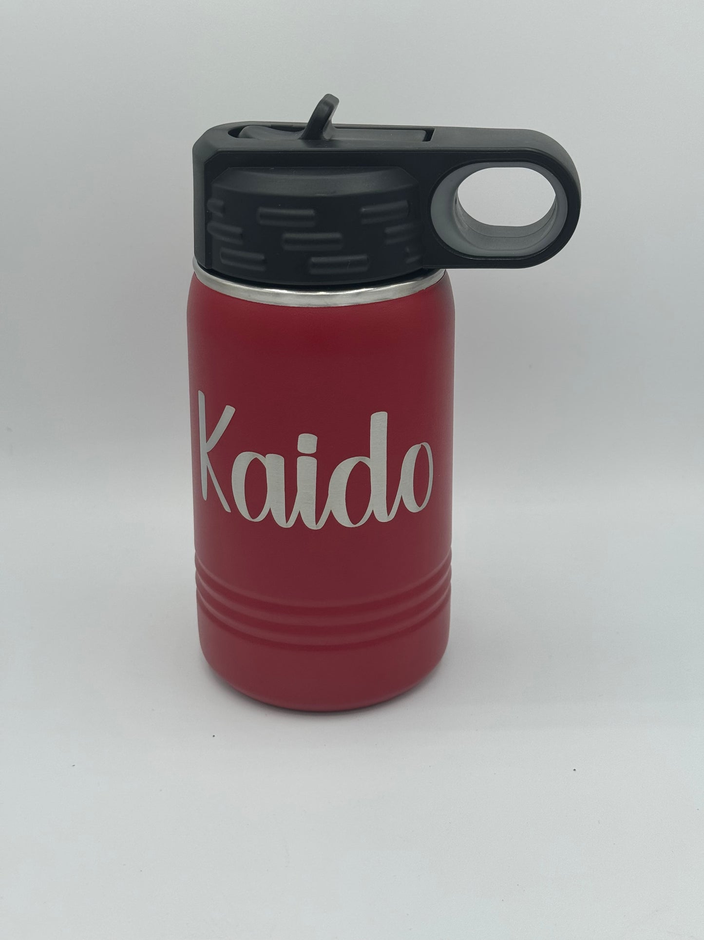 "Custom personalized red Polar Camel 12oz stainless steel kids' water bottle with a black flip-top lid and handle. The bottle features an engraved name 'Kaido' in a stylish, bold script font."