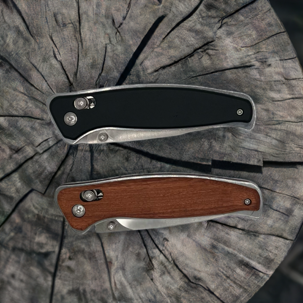 Two personalized Bison River folding pocket knives displayed on a rustic wood surface—one with a sleek black handle and the other with a classic wood handle. Both feature stainless steel frames and precision craftsmanship, ideal for engraving.