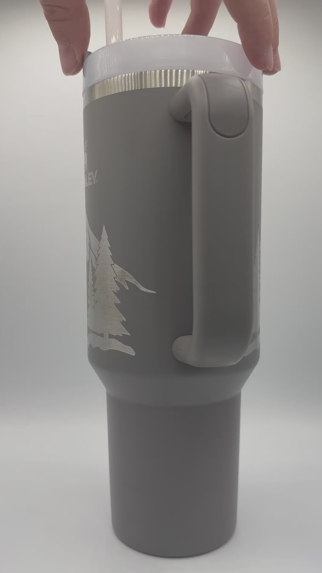 "Video showcasing a custom personalized gray 40oz Stanley tumbler, featuring an engraved design with a name and unique artwork. The video highlights the tumbler’s sleek finish, sturdy handle, and intricate personalization details, making it a stylish and functional accessory."