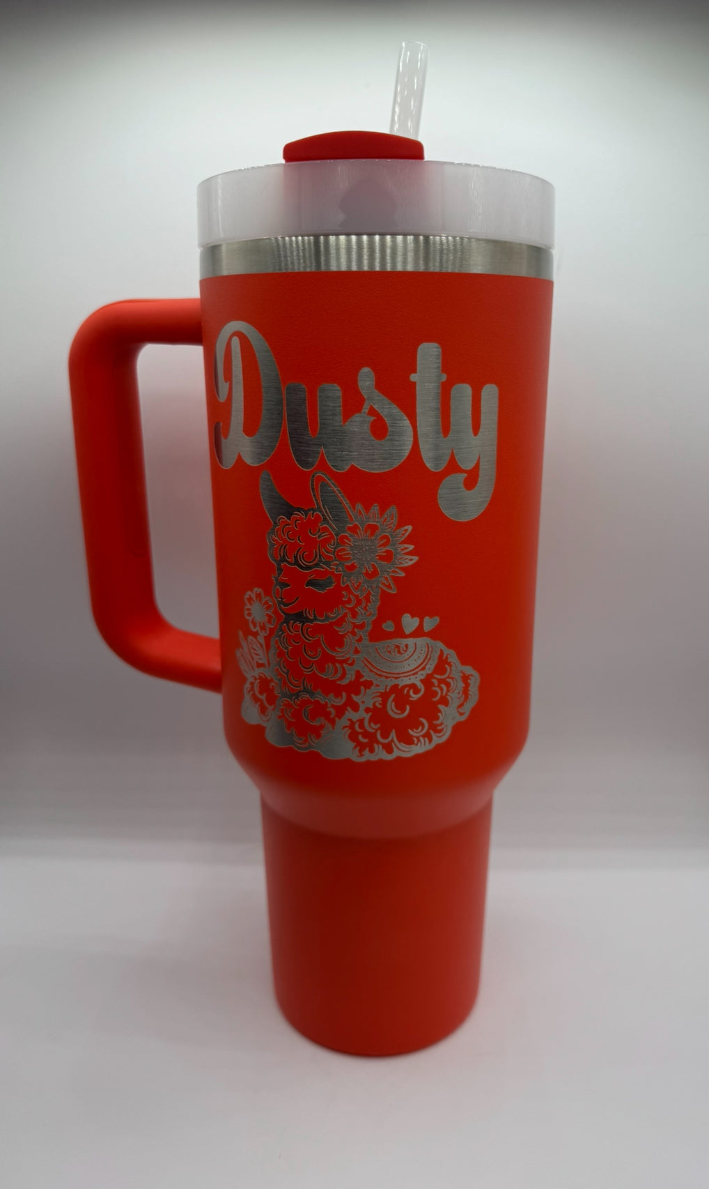 "Custom personalized orange 40oz Stanley tumbler featuring a stylish engraved name 'Dusty' in a bold script font, along with an intricately detailed illustration of a fluffy, decorated llama with floral accents. A unique and vibrant design perfect for personal use or as a thoughtful gift!"
