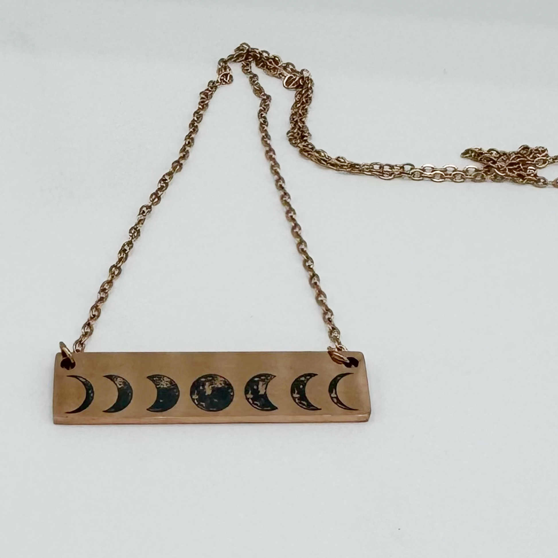 "Personalized rose gold horizontal bar necklace featuring an engraved moon phase design, perfect for celestial jewelry lovers."